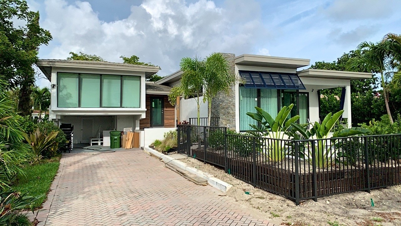 Completed house and addition from the driveway, showing the paver drive, wood-clad entry and new planting