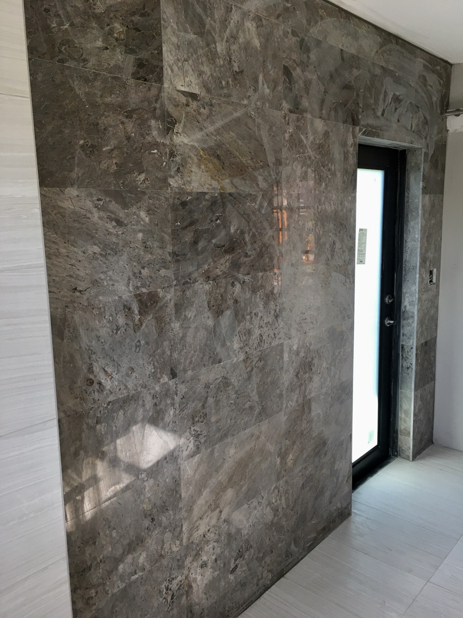 Full-height marble slab feature wall beside a glass entry door