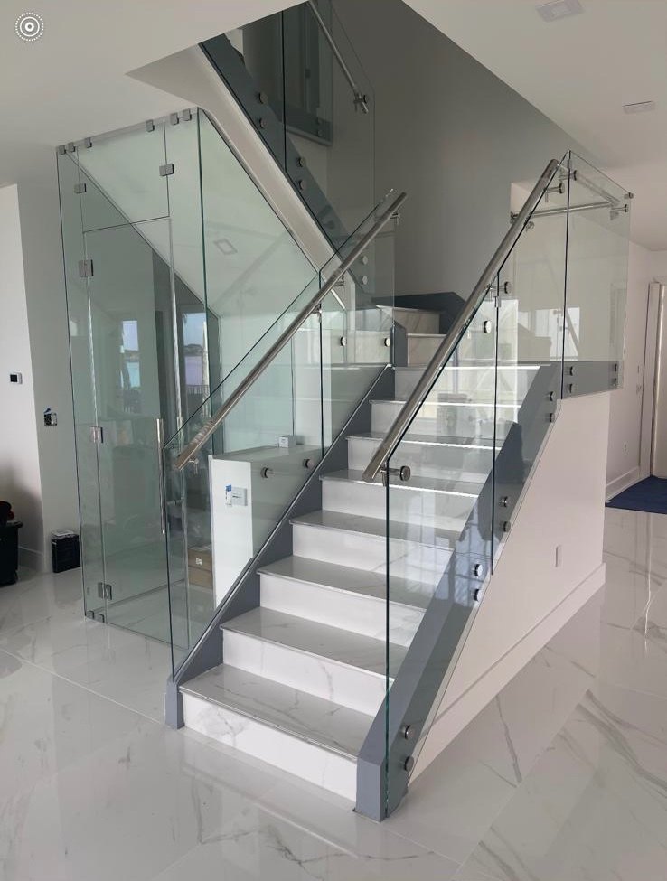 Completed staircase with frameless glass railings, stainless steel handrails and marble-look porcelain treads and flooring