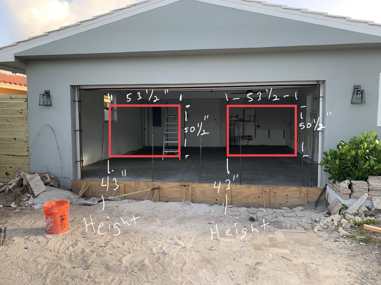 Former garage opening with new window dimensions marked in red on the concrete block