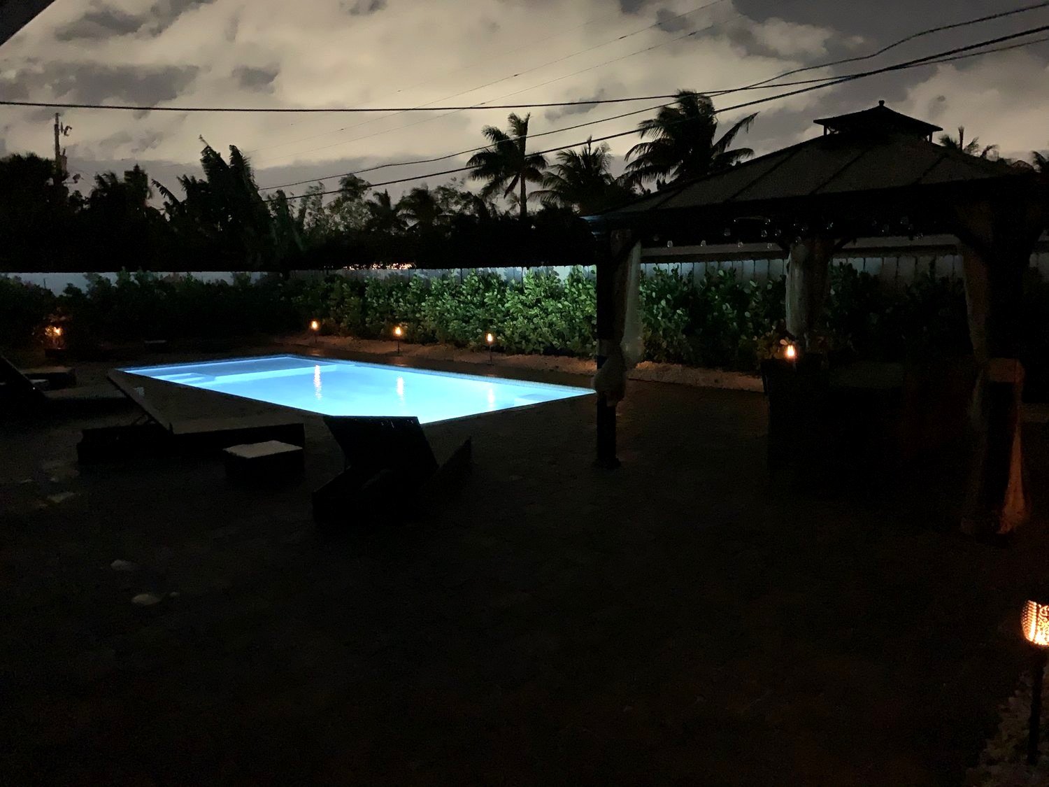 The finished pool and deck at night with pool and landscape lighting on