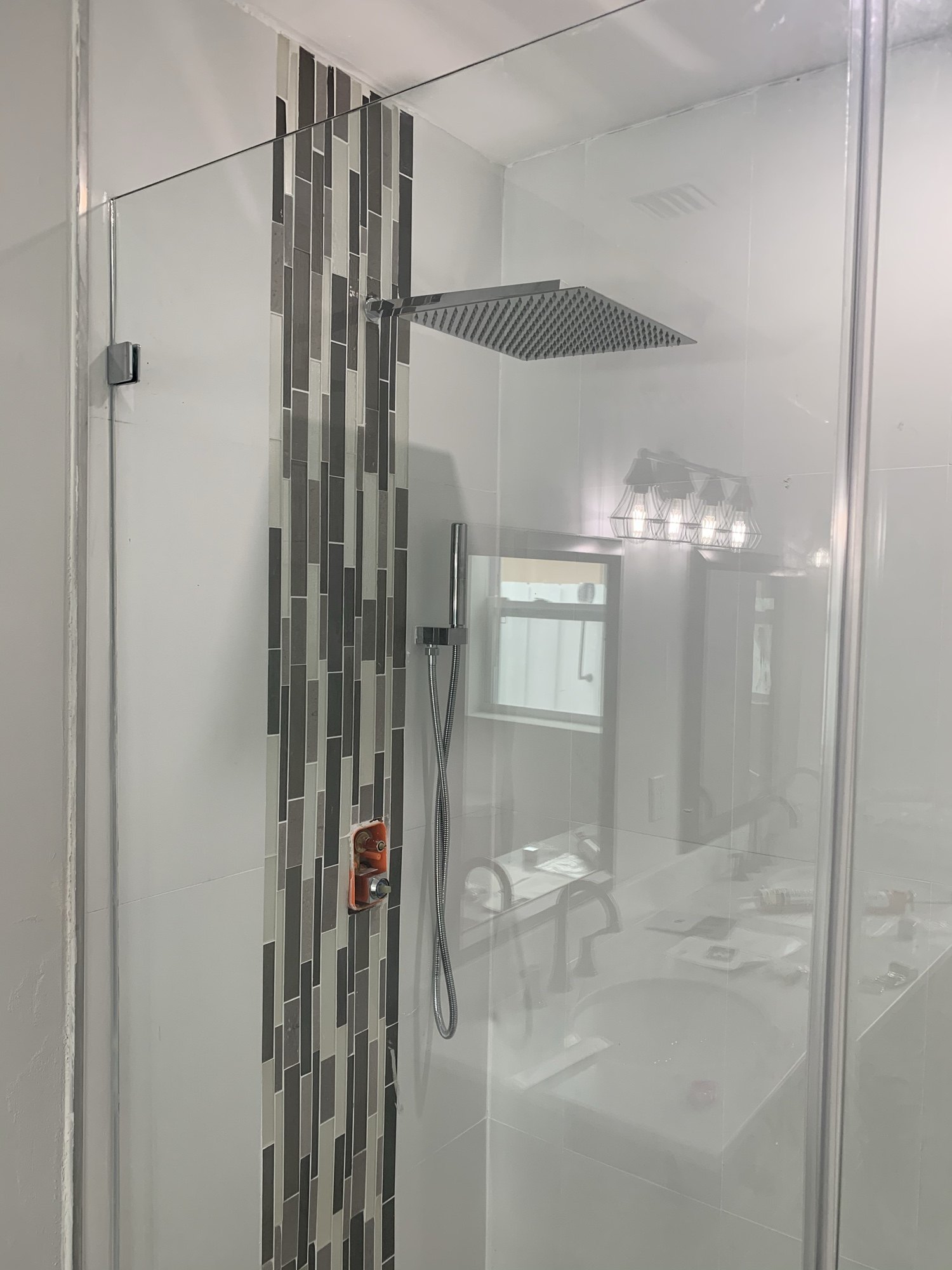 Finished tiled shower with a rain head, glass enclosure and recessed lighting