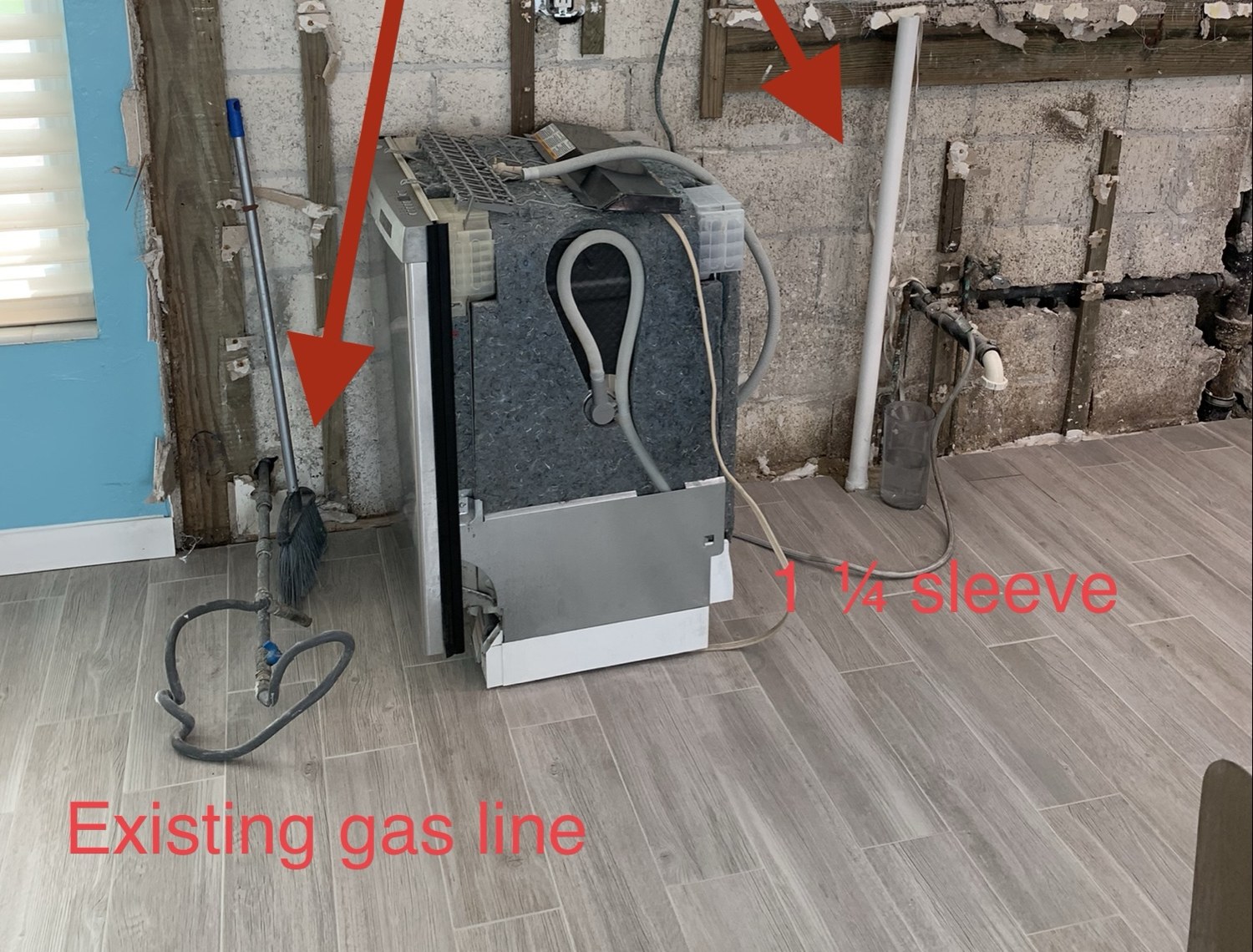Opened wall with red arrows marking the existing gas line and a sleeve size