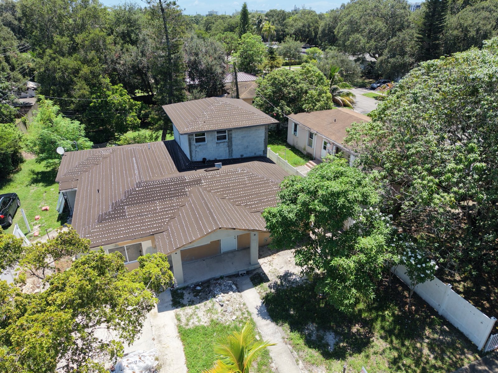 Aerial view of the reroofed single-story home with the new second-story block structure behind it