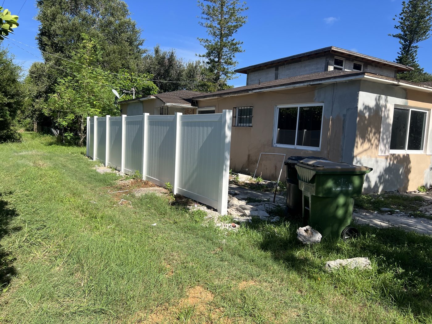 New white vinyl privacy fence installed along the property line beside the home