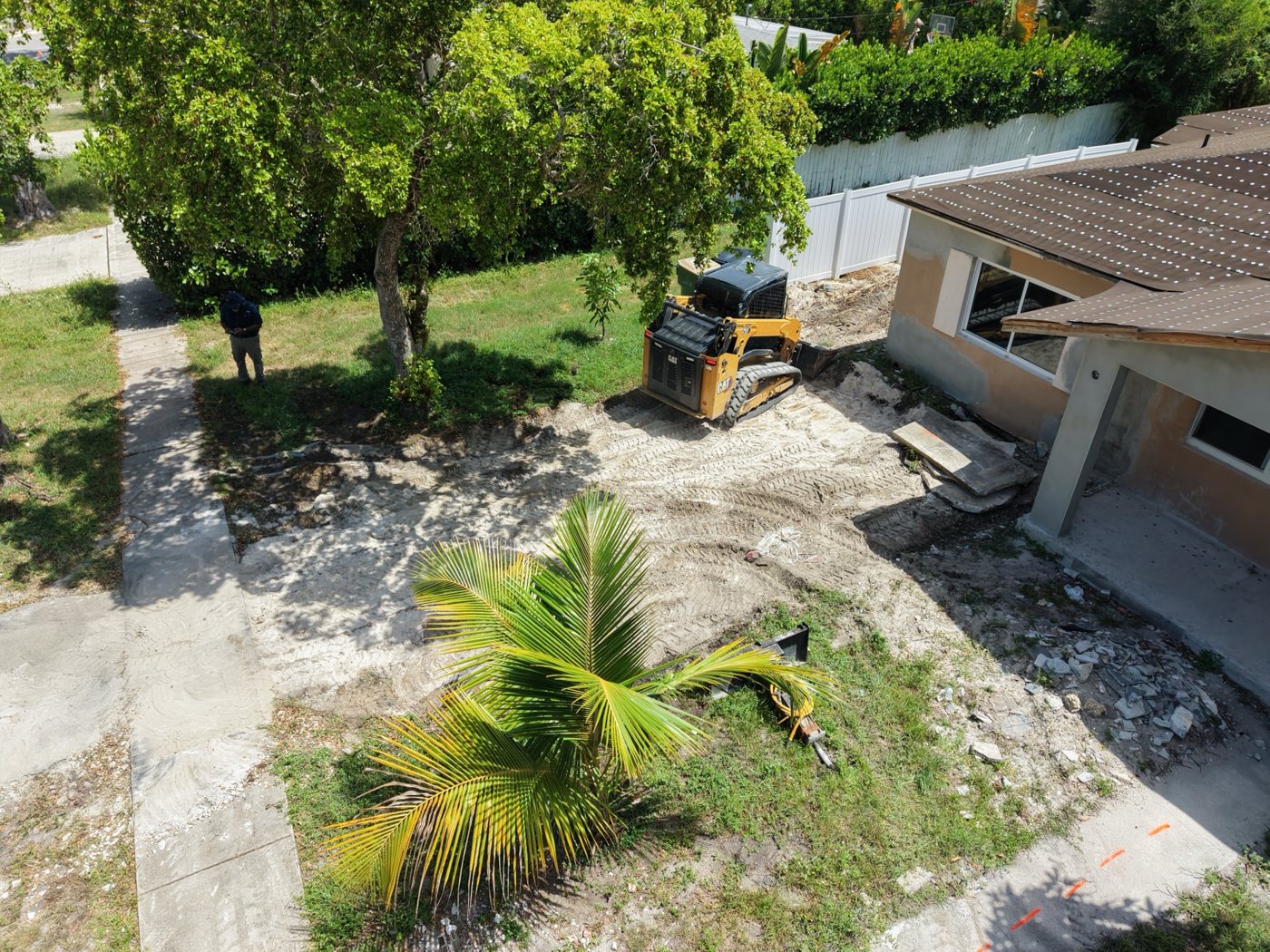 Compact track loader grading the side yard of a home under renovation