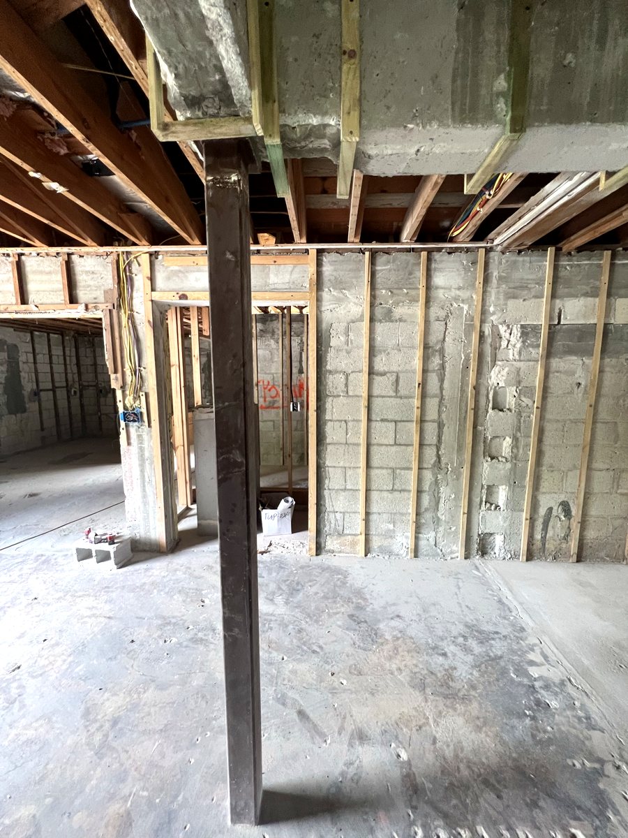 Interior gut renovation showing a new structural steel column supporting a concrete tie beam