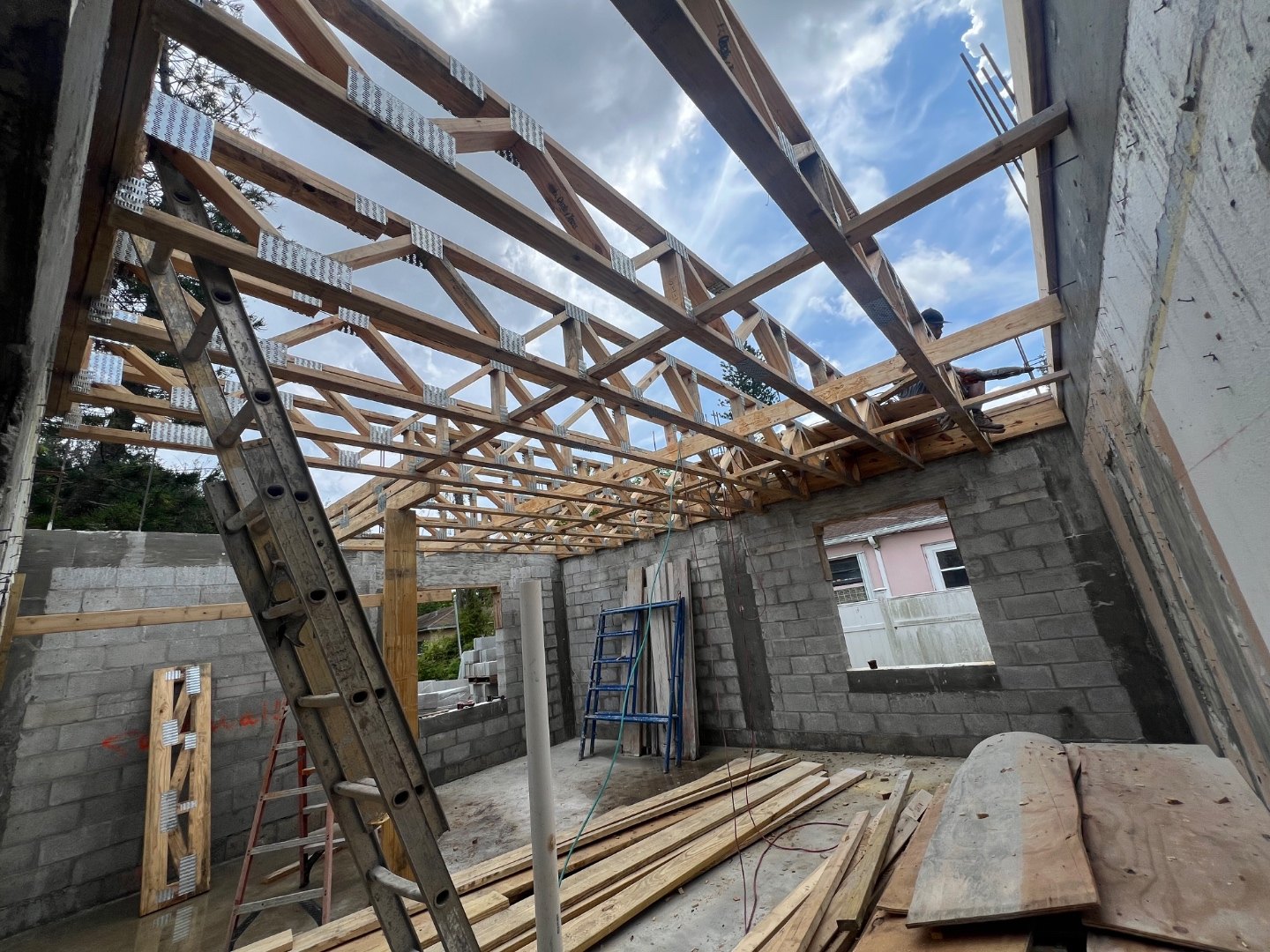 Wood roof trusses set across the new block walls, seen from inside the structure