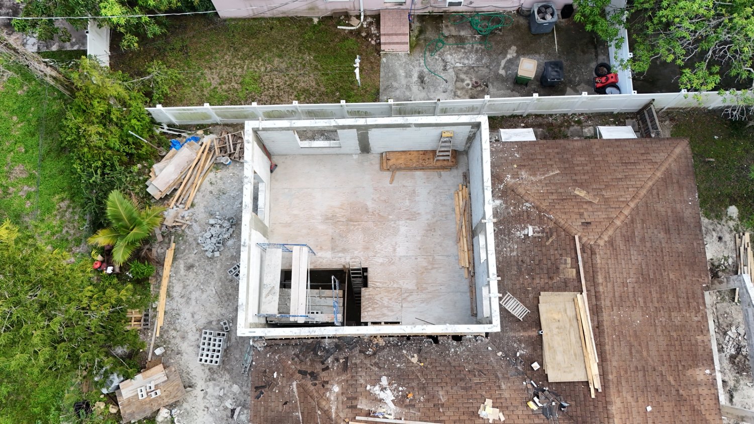 Overhead drone view documenting the concrete block walls and framing layout of a home addition in progress