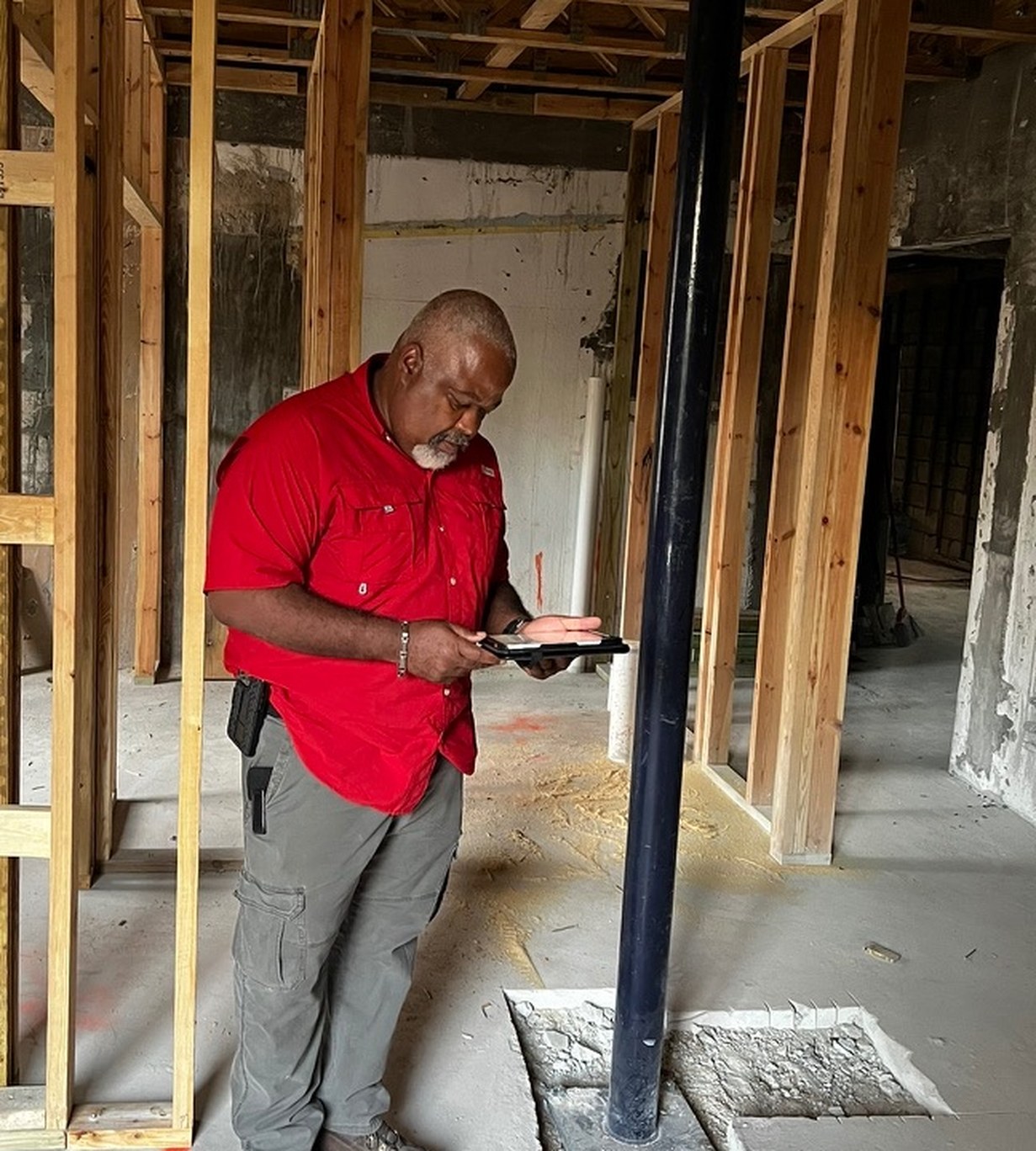 Construction drawings reviewed on a tablet on site beside a new structural steel column and interior framing